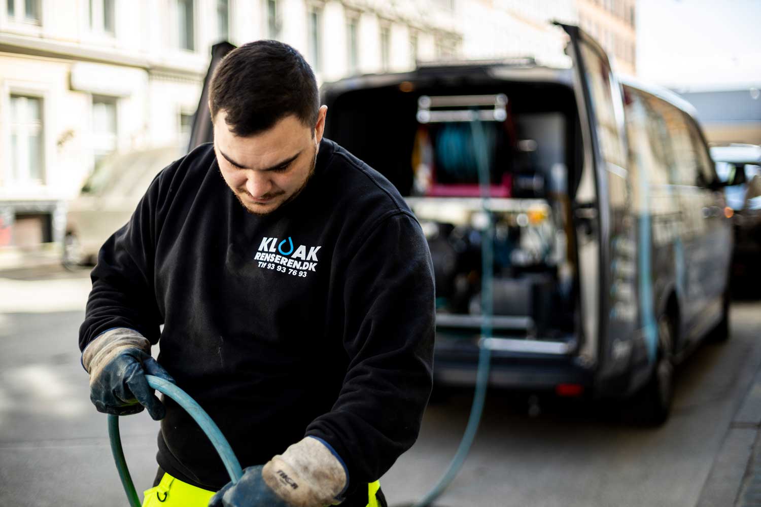 Kloakmand arbejder med kloakrensning udendørs.
