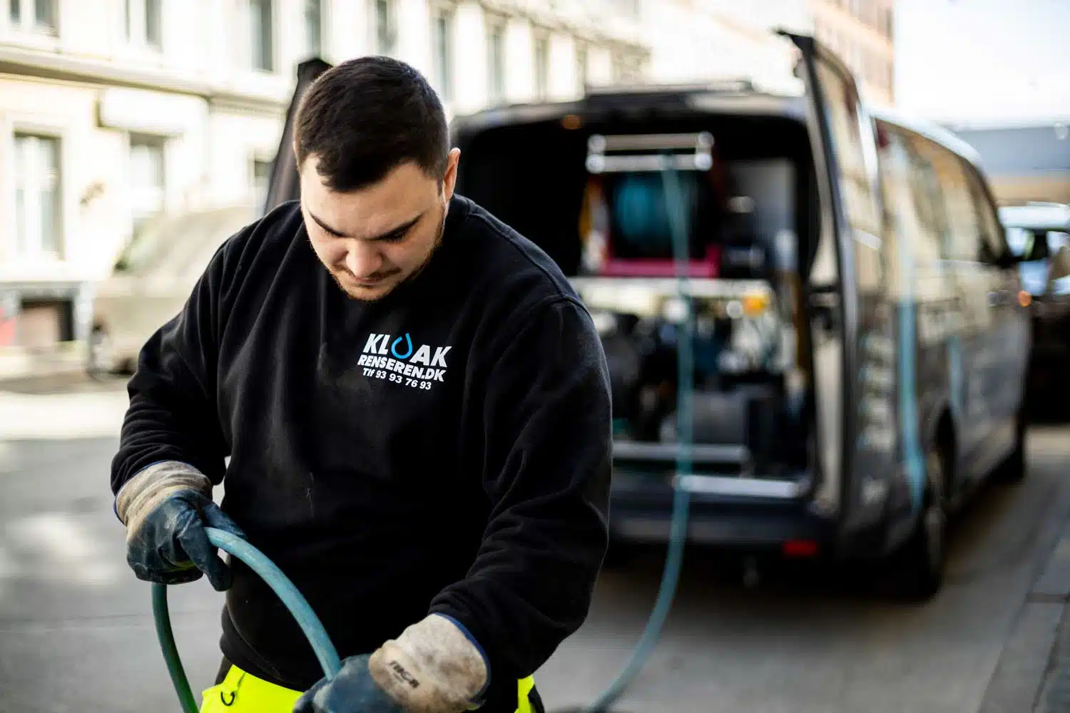 Kloakmand arbejder med kloakrensning udendørs.